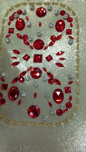 Macro detail of red and clear crystals hand-sewn onto champagne glitter fabric