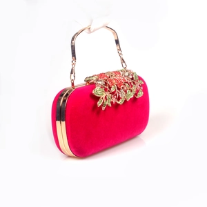 Macro view of velvet evening clutch featuring gold leaf flower clasp with colorful rhinestones