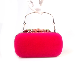 Detailed view of magenta velvet clutch featuring colorful crystal flower and gold handle