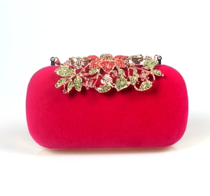 Detail of rose red velvet evening bag featuring a gold floral clasp with red crystals