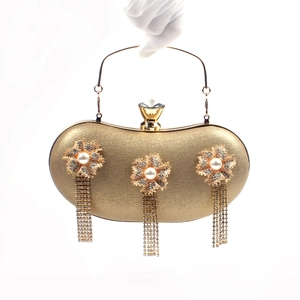 Detail of golden evening clutch with pearl flower ornaments and long rhinestone tassels