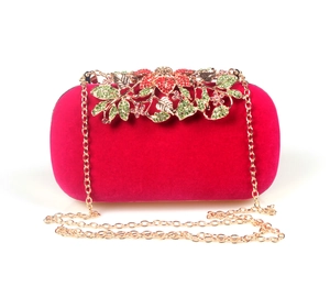 Detail of red velvet evening bag featuring gold leaf metalwork and colorful crystals