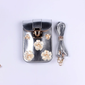 Detail der silbernen Handytasche mit weißen 3D-Blumenblättern und Perlenakzenten