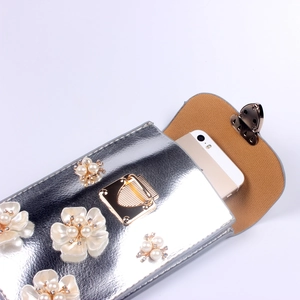 Detailsicht der silbernen Handytasche mit Perlenblumen und goldenem Herzschloss