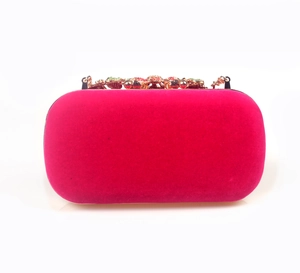 Close-up of golden floral clasp and rhinestones on fuchsia velvet evening clutch bag