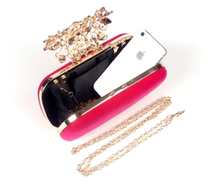 Detail of rose red velvet evening clutch with golden floral clasp and chain