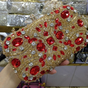 Detail of a handmade gold evening clutch bag with red crystals and rhinestone embellishments