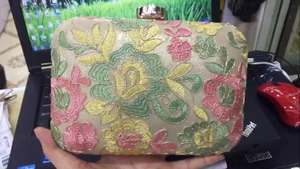 Close-up of floral embroidery evening clutch bag with golden metal clasp detail
