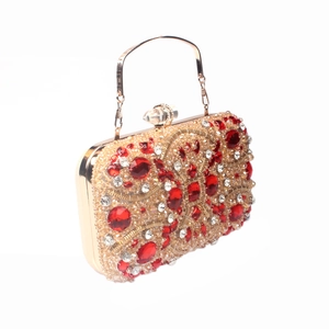 Detailed view of luxury evening clutch bag with red crystals and golden frame