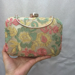 Detail of floral embroidery and gold metal frame on an elegant evening clutch bag