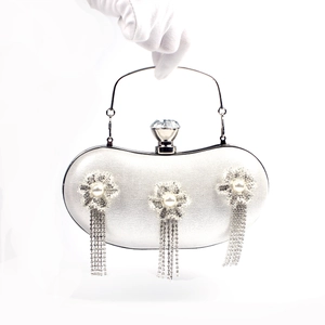 Detail of silver evening clutch featuring pearl rhinestone flowers and long tassel fringe