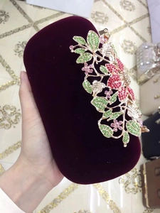 Detail of burgundy velvet clutch featuring colorful crystal rhinestones and metal floral leaves
