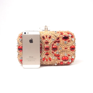 Detailed comparison of red crystal evening bag next to an iPhone for size reference