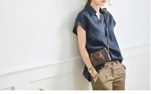 Dettaglio camicia in lino blu navy con scollo a V e borsa per fotocamera marrone vintage