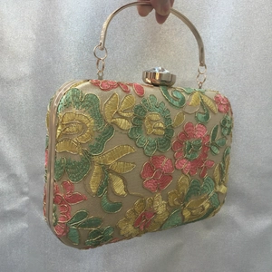 Macro detail of floral embroidery and crystal clasp on vintage champagne evening bag