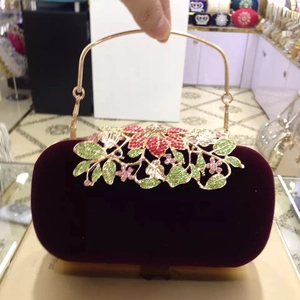 Detail of burgundy velvet evening bag with ornate crystal floral clasp and gold handle