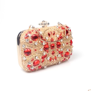 Detail of red crystals and champagne rhinestones on a gold frame evening clutch bag