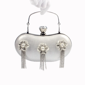Detail of silver evening clutch with crystal tassels and 3D pearl flowers on white background