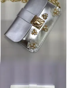 Dettaglio di una borsa a tracolla in PU bianco con fiori di perle e catena dorata