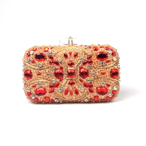 Macro shot of handcrafted gold metal evening clutch with red crystal flower pattern