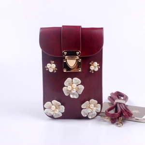 Detail der weinroten Handytasche mit floralen Perlenakzenten und Gold-Metallschnalle