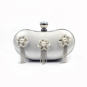 Detail of silver evening clutch with silk texture, pearl flowers and rhinestone tassels
