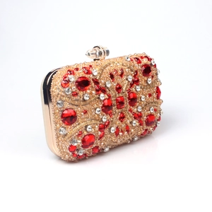 Macro view of gold beaded evening clutch with red crystal gemstone embellishments