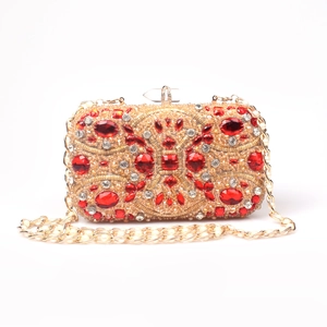 Detail of evening clutch featuring red gemstones, white crystals and pearl gold chain