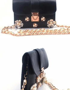 Dettaglio mini borsa a tracolla in pelle nera con fiori di perle e chiusura dorata