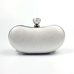 Close-up of silver evening clutch bag featuring pearlescent fabric and crystal clasp