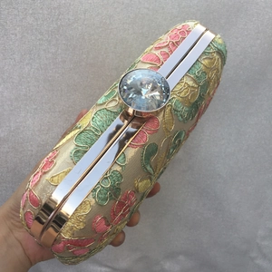 Close-up of floral embroidery detail and crystal clasp on evening clutch bag