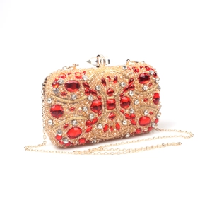 Detail of red crystals and gold beads on a luxury evening clutch with metal chain