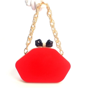 Detail of red velvet evening bag with gold chain and black crystal bow clasp