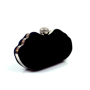 Detailed view of black velvet evening bag with gold metal frame and crystal clasp