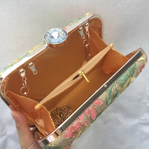 Interior detail of floral embroidered clutch with champagne lining and gold chain strap