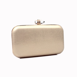 Close-up of golden evening clutch with crystal top clasp and smooth metallic finish