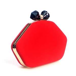 Close-up of red velvet evening clutch with gold metal frame and jewel clasp