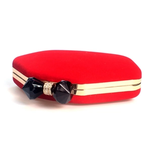 Detail of red velvet evening clutch with golden metal frame and diamond bow clasp