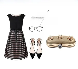 Golden clutch bag featuring pearl rhinestone flowers paired with a black striped dress