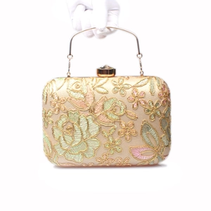 Detail of floral embroidery on evening clutch with gemstone clasp and gold handle
