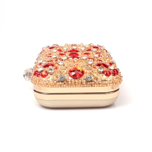 Detailed macro of gold metal frame luxury evening clutch with red and amber crystals