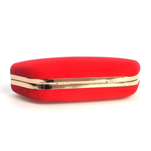 Macro detail of red velvet evening clutch featuring a premium gold metallic frame