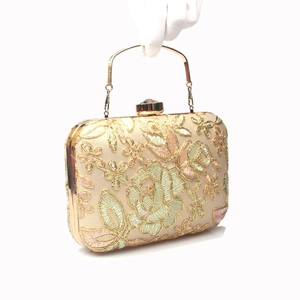 Close-up of floral embroidery on evening clutch with gold metal frame and crystal clasp