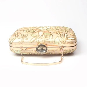 Detail of floral embroidery, large rhinestone clasp and metal handle on gold evening bag