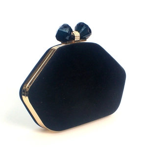 Detail of velvet evening bag with gold frame and blue gemstone closure on white background