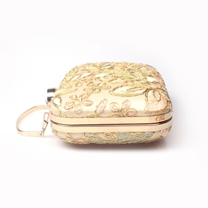Detailed close-up of champagne lace clutch with floral embroidery and gold metal hardware