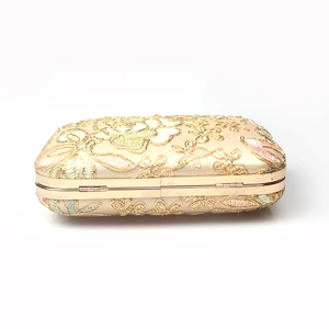 Macro shot of colorful floral embroidery on a satin evening clutch with gold metal frame