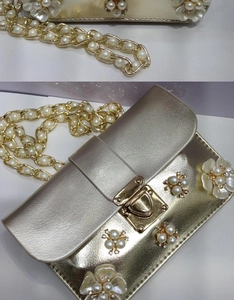 Dettaglio della pochette dorata con fiori 3D, perle e decorazioni in cristallo