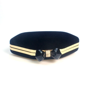 Detail of black velvet hexagon evening clutch with golden frame and crystal bow clasp