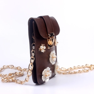 Detail der braunen Kunstledertasche mit 3D-Blumen und dekorativer Perlenkette
